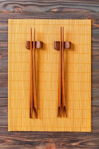 Dos juegos de palillos de sushi sobre fondo de bambú de madera, vista superior —  Fotos de Stock