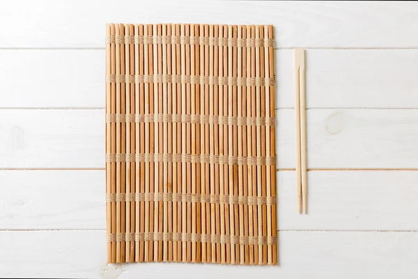 Dva sushi hůlky s prázdnou bambusovou rohoží nebo dřevěnou deskou na dřevěném pozadí zobrazení nahoře se Stace kopií — Stock fotografie