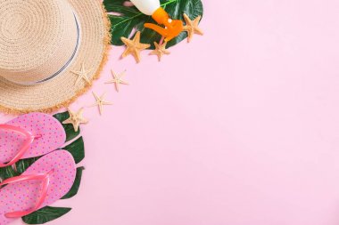 Kopya alanı ile pembe arka plan üst görünümünde hasır şapka, güneş kremi şişesi ve seastar ile Plaj aksesuarları