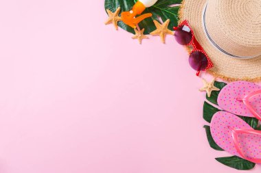 Kopya alanı ile pembe arka plan üst görünümünde hasır şapka, güneş kremi şişesi ve seastar ile Plaj aksesuarları