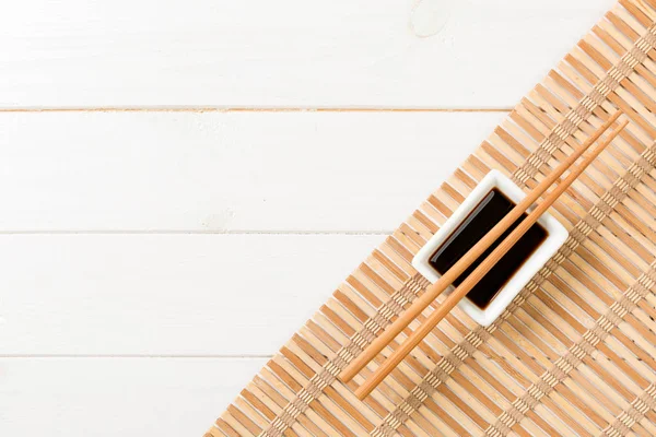 Bambusovou rohožku a sójové omáčky se Suši na bílém dřevěném stole. Zobrazení nahoře s pozadím pro zkopírování místa pro sushi. Plochá ležela — Stock fotografie