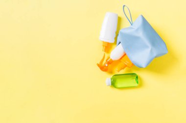 Kadın kozmetik çanta güneş kremi sprey, sunsreen, güneş kremi ve vücut losyonu ve spf krem kopya alanı ile sarı arka plan dolu üst görünümü. Tam üstünde. Parlak yaz konsepti