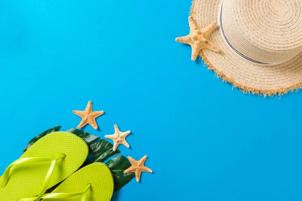Accesorios de playa con sombrero de paja y conchas marinas sobre fondo azul vista superior con espacio para copiar — Foto de Stock