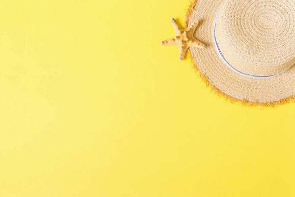 yellow retro straw hat with seastar top view with copy space. summer concept on yellow background