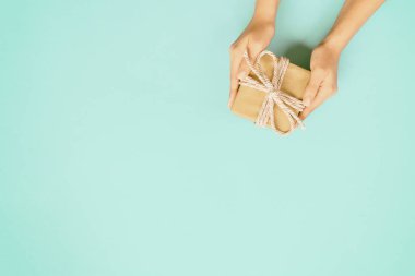 Hediye kutusu renk arka plan, üstten görünüm üzerinde pembe kurdele ile tutan kadın kolları