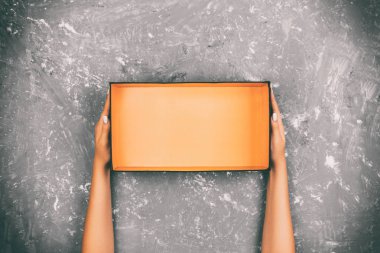 Gri arka plan üzerine açık boş kutu holding kız eller