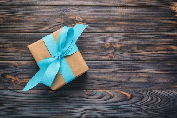 纸礼品盒与蓝色丝带在深色木背景。带复制空间的顶部视图 — 图库照片