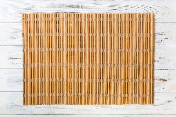 Töm asiatisk mat bakgrund. brun bambu matta på wnite trä bakgrund uppifrån med kopiera utrymme platt Lay — Stockfoto