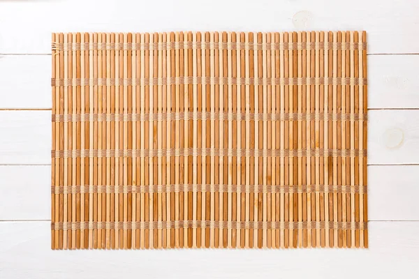Prázdné asijské pozadí jídla. hnědá bambusový rohož na wnitém dřevěném podkladu s plochou kopií — Stock fotografie
