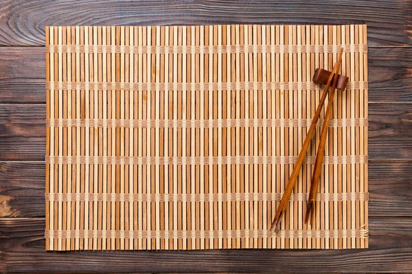 Dos palillos de sushi con estera de bambú marrón vacío o placa de madera sobre fondo de madera Vista superior con espacio para copiar. vacío asiático alimentos fondo —  Fotos de Stock