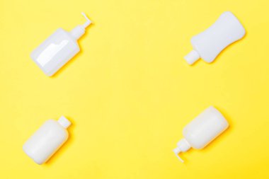 Sarı arka planda izole beyaz Kozmetik Konteynerler seti, kopya alanı ile üst görünüm. Size tasarım için boş alan ile plastik vücut bakımı şişe kapları grubu