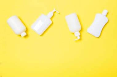 Sarı arka planda izole beyaz Kozmetik Konteynerler seti, kopya alanı ile üst görünüm. Size tasarım için boş alan ile plastik vücut bakımı şişe kapları grubu