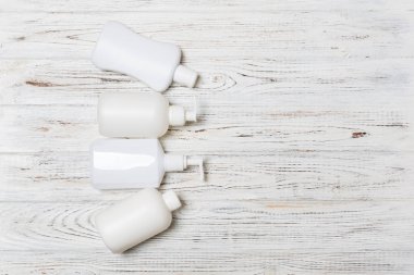 Ahşap arka plan üzerinde Beyaz Kozmetik kaplar seti, kopya alanı ile üst görünümü. Tasarım için boş alana sahip plastik vücut bakım şişe kapları Grubu