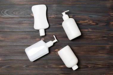 Ahşap arka plan üzerinde Beyaz Kozmetik kaplar seti, kopya alanı ile üst görünümü. Tasarım için boş alana sahip plastik vücut bakım şişe kapları Grubu