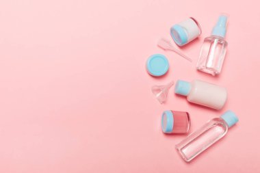 Pembe arka plan üzerinde kozmetik ürünler için küçük seyahat şişe ve kavanoz üst görünüm kompozisyon. Tasarımınız için kopyalama alanı ile yüz cilt bakım konsepti