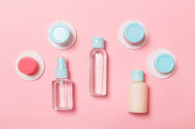 Pembe arka planda seyahat etmek için bir grup küçük şişe. Fikirlerin için uzayı kopyala. Kozmetik ürünlerin düz bileşimi. Pamuklu krema kaplarının üst görüntüsü
