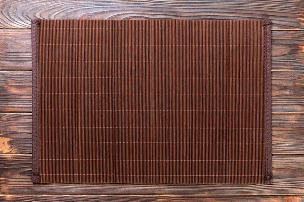 Пустая азиатская еда. Темный бамбуковый коврик на деревянном фоне сверху с плоским пространством для копирования — стоковое фото