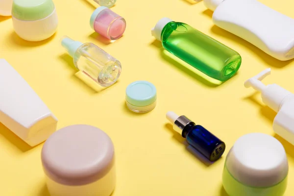 Composição de frascos e garrafas de cosméticos de diferentes tamanhos sobre fundo amarelo. Conceito de cuidados de beleza com espaço de cópia — Fotografia de Stock