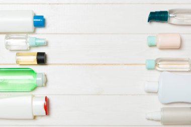 Beyaz ahşap arka plan üzerinde kozmetik için farklı kozmetik şişe ve konteyner üst görünümü. Kopyalama alanı ile düz döşeme kompozisyonu