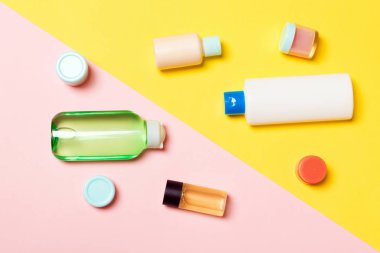 Pembe arka planda kozmetik kaplar, spreyler, kavanoz ve şişeler üst görünümü. Tasarımınız için boş alana sahip yakın çekim görünümü