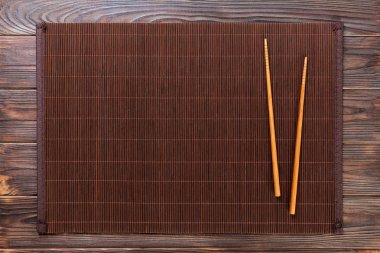 kopya alanı ile ahşap Arka Plan Üst görünümünde boş bambu paspas veya ahşap plaka ile iki suşi çubukları. boş asya gıda arka plan