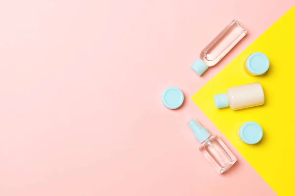 Draufsicht auf verschiedene Kosmetikflaschen und Kosmetikbehälter auf rosa und gelbem Hintergrund. Flache Lagekomposition mit Kopierraum — Stockfoto