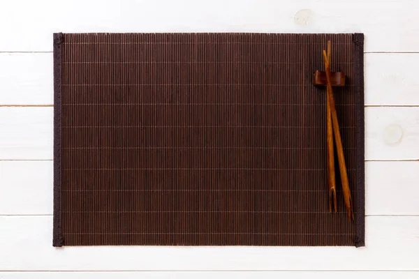 Två sushi ätpinnar med Tom bambu matta eller träplatta på vit trä bakgrund uppifrån med kopia utrymme. Töm asiatisk mat bakgrund — Stockfoto