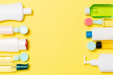 Sarı arka planda farklı ölçekli Kozmetik Kavanozlar ve şişeler bileşimi. Kopya alanı ile güzellik bakımı konsepti