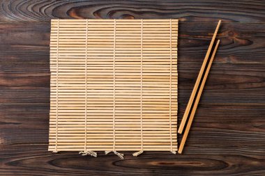 kopya alanı ile ahşap Arka Plan Üst görünümünde boş kahverengi bambu paspas veya ahşap plaka ile iki suşi çubukları. boş asya gıda arka plan