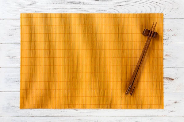 Dos palillos de sushi con estera de bambú amarillo vacío o placa de madera sobre fondo de madera blanca Vista superior con espacio para copiar. vacío asiático alimentos fondo —  Fotos de Stock