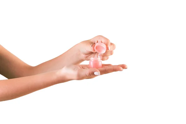 Mão feminina segurando creme garrafa de loção isolada. Garota frasco de abertura produtos cosméticos no fundo branco — Fotografia de Stock