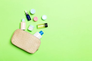 Yeşil arka planda kozmetik ürünleri bırakılan kadın kozmetik çanta üst görünümü. Kopya alanı ile Bodycare kavramı