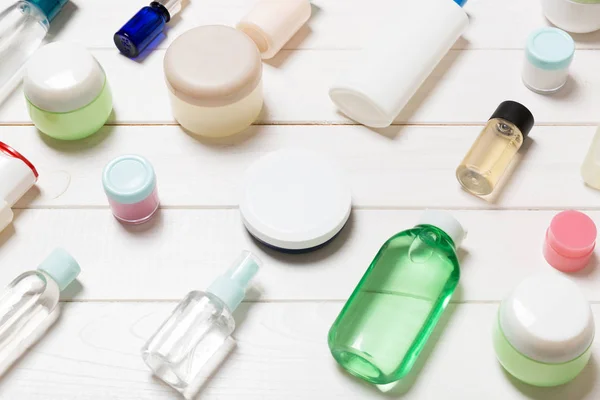 Vista de cerca de botellas de cosméticos, frascos, recipientes y aerosoles sobre fondo de madera blanca. Concepto de belleza con espacio de copia —  Fotos de Stock