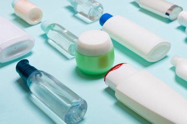 Mavi arka planda farklı kavanoz ve şişeler kozmetik ürünlerin üst görünümü. Kopyalama alanı olan kapsayıcıların yakın çekim