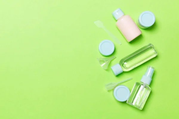 Zusammensetzung von kleinen Reiseflaschen und Dosen für Kosmetikprodukte auf grünem Hintergrund. Gesichtspflegekonzept mit Kopierraum für Ihr Design — Stockfoto