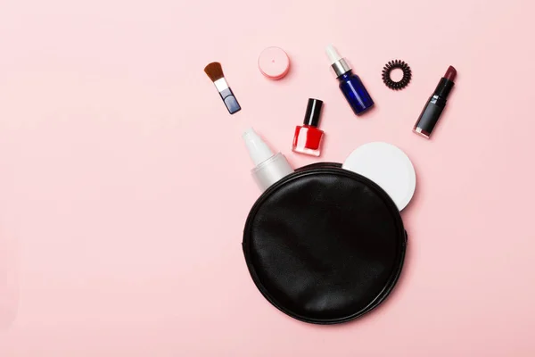 Top view of set of make up and skin care products spilling out of cosmetics bag on pink background. Beauty concept — Stock Photo, Image