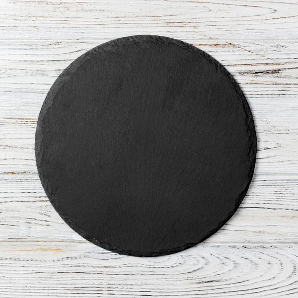 Czarna okrągła płyta na drewnianym tle, widok z góry, przestrzeń kopiowana — Zdjęcie stockowe