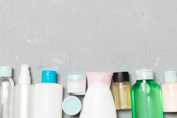 Composición plana con botellas cosméticas y de crema sobre fondo de cemento. Concepto de productos de belleza con espacio de copia —  Fotos de Stock