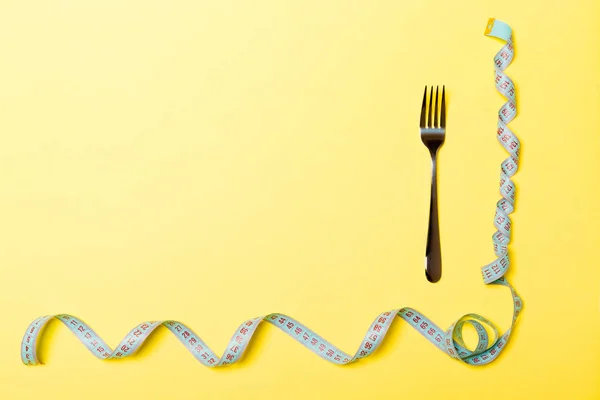 Top view of fork and curled measuring tape on yellow background. Diet concept with copy space — Stock Photo, Image