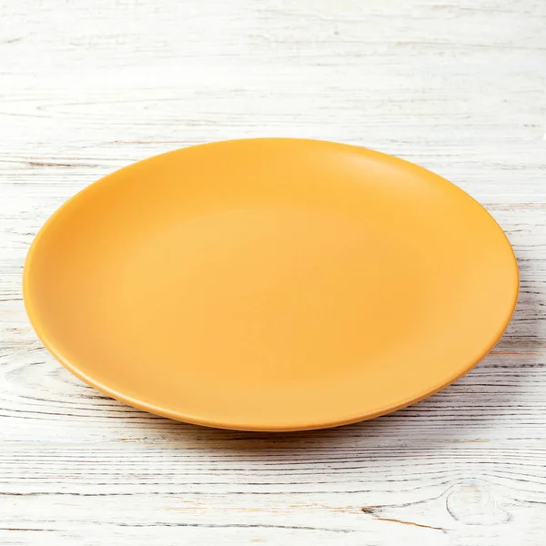 Placa redonda amarela no fundo da mesa de madeira. Visão superior, modelo para o seu design — Fotografia de Stock