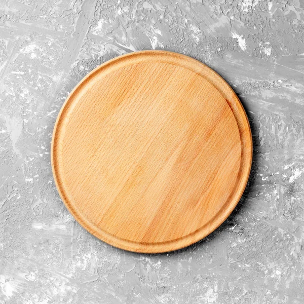 Empty round wooden dish on table over gray cement wall backgroun — Stock Photo, Image