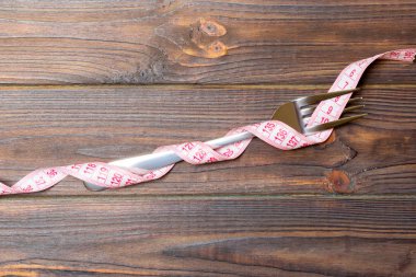 Çatal üst görünümü ile ahşap arka plan üzerinde ölçüm bandı sarılır. Kilo kaybı için diyet Kavramı