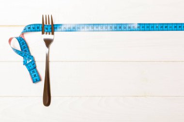 Yaratıcı fikirleriniz için yer olan ahşap arka plan üzerinde çatal ve ölçüm bandı ile obezite konseptinin en iyi görünümü