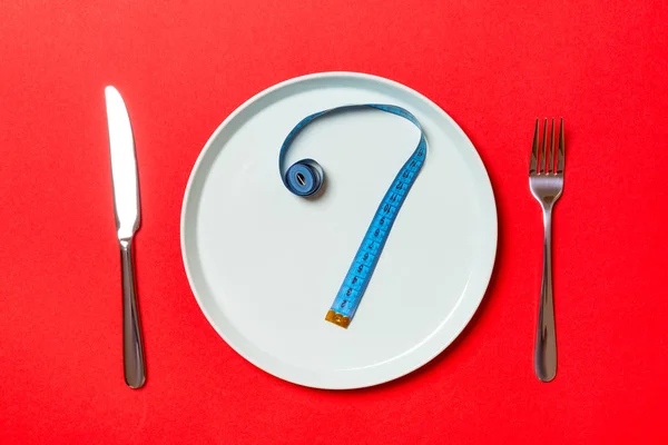 Question mark made of measuring tape on round plate on red background. Top view of hesitation and diet concept — Stock Photo, Image