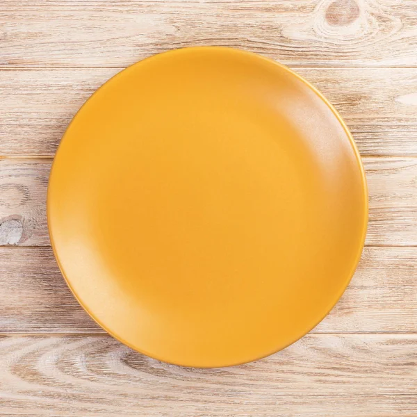 Gele ronde plaat op houten tafel achtergrond. Top View, sjabloon voor uw ontwerp — Stockfoto