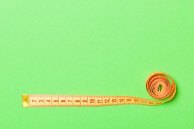 Yeşil arka plan üzerinde ölçüm bandı yapılmış çerçeve. Dikiş konseptinin en iyi görünümü. Tasarımınız için boş alana sahip ince bel konsepti