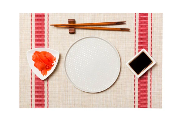 Tom rund vit tallrik med ätpinnar för sushi och sojasås, ingefära på sushimatta bakgrund. Toppvy med kopierings utrymme för dig design — Stockfoto
