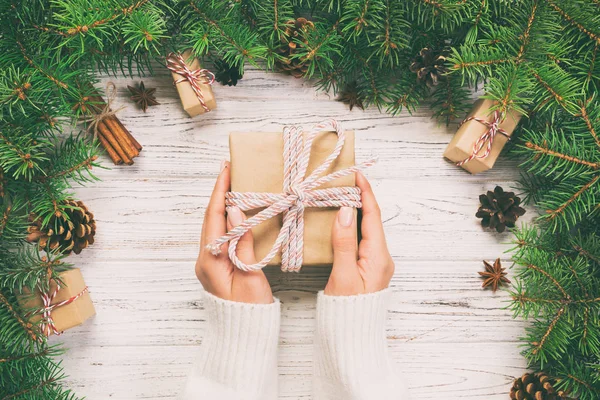 Vrouwelijke handen houden Wrapping Christmas Gift Box met roze lint op witte houten tafel. Bovenaanzicht. Afgezwakt — Stockfoto