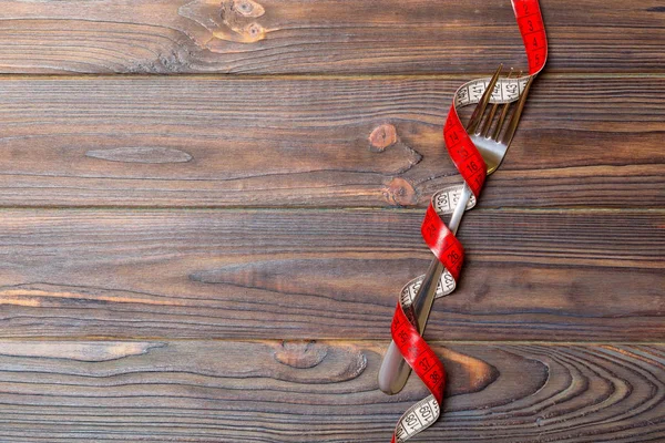 Composición de cinta métrica envuelta en rizos y tenedor sobre fondo de madera con espacio vacío para su diseño. Concepto de sobrepeso — Foto de Stock