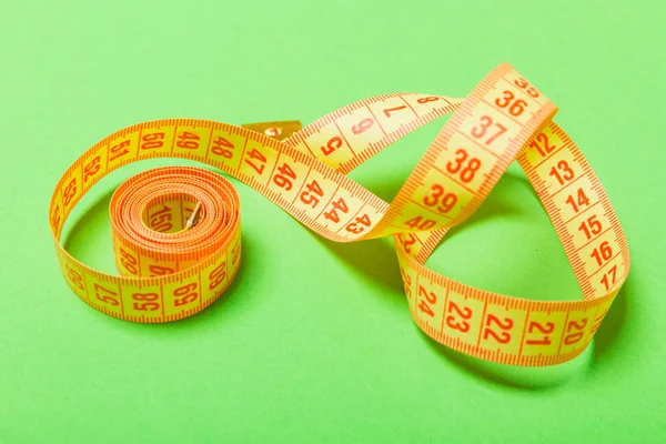 Uzavřete zamotané měřicí pásky na zeleném pozadí. Fitness a zdravá strava s perspektivním výhledem — Stock fotografie
